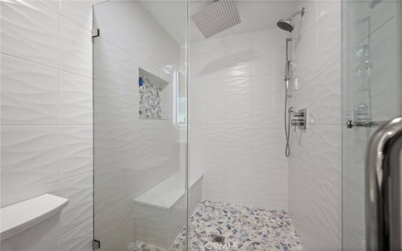 Primary bath room with double sinks and walk-in shower with seat and rain shower