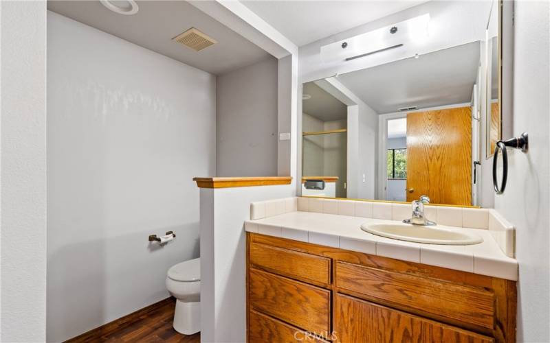 This ensuite bathroom is a ¾ bath with doors to both the primary bedroom and main living space. It boasts laminate flooring and tiled countertop and shower.