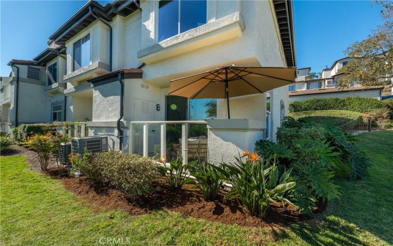 Patio side of home with umbrella.  Notice the larger tonnage A/C condenser the new owners benefit!