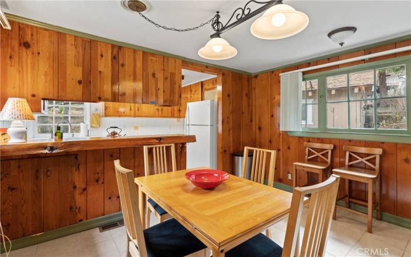 Here is a cozy dining room and kitchen with knotty pine wood walls.