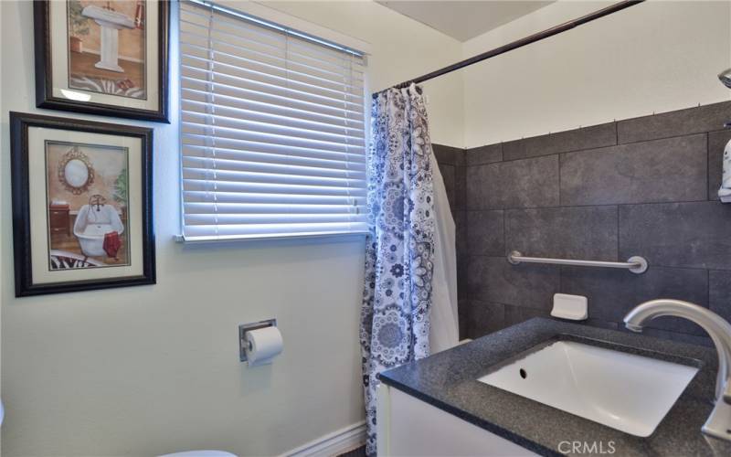 The bathroom features newer flooring, vanity with backsplash and custom tiled shower/tub combo