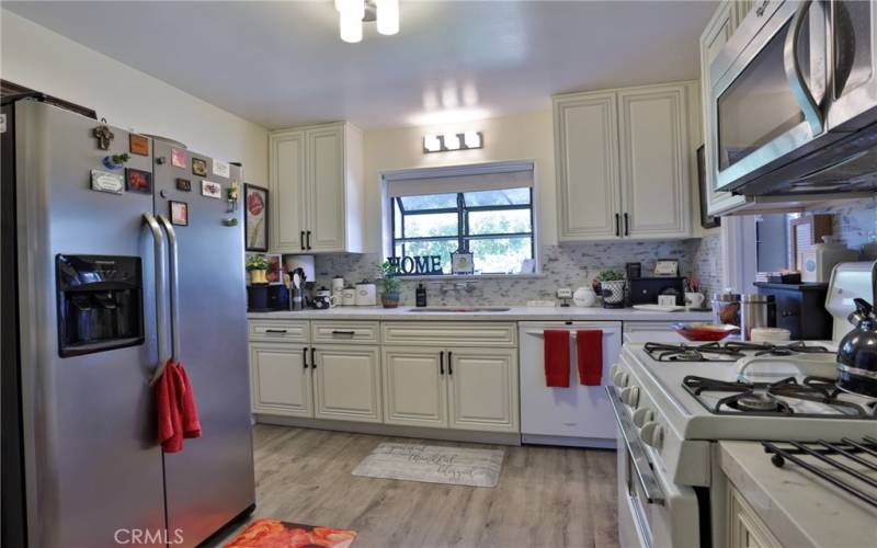 The kitchen features, newer flooring, newer quartz countertops, beautiful backsplash, garden window looking out to the back yard, dishwasher, 4 burner gas stove and microhood and the refrigerator stays!