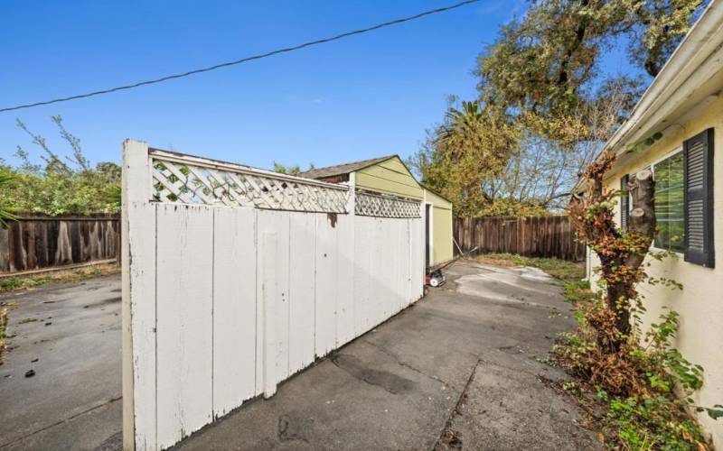 There is fence that divides rear yard from main house. 2 buildings on left are storage sheds