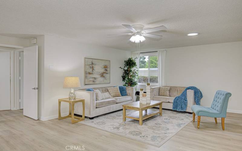 Large living room features a wall heat pump, ceiling fan and multiple solar tubes which bring in natural sunlight.