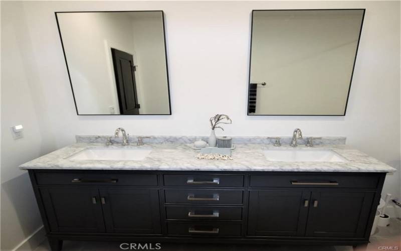 Dual sinks with marble gray countertops and rich darker wood cabinetry.