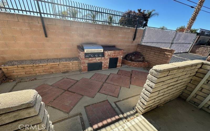 Back yard with a stainless steel barbeque built in.