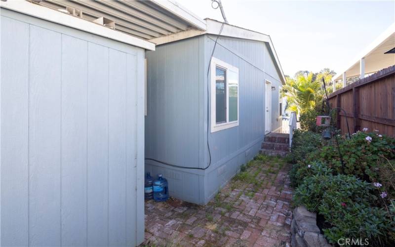 Behind the shed on the side of the house where the master bedroom is located.