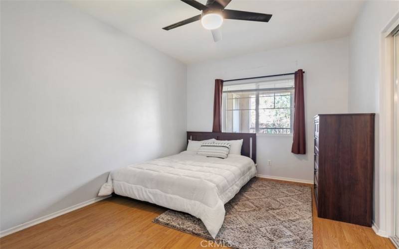 A cozy bedroom with soft natural light, a remote activating ceiling fan that makes it the perfect retreat for rest and relaxation.