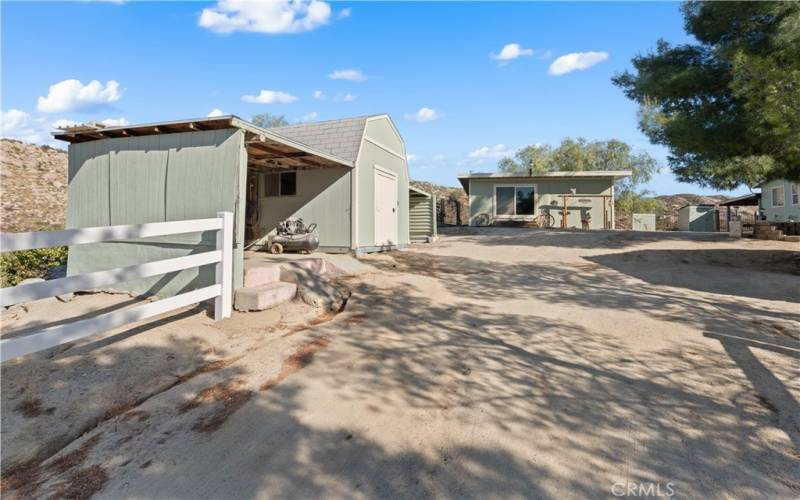 2nd home driveway with shed and covered storage/work spaces on both sides. Also looking at the additional building.