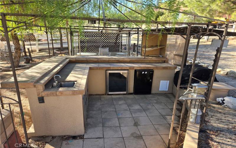 Outdoor kitchen with sink, mini fridges and built-in grill.