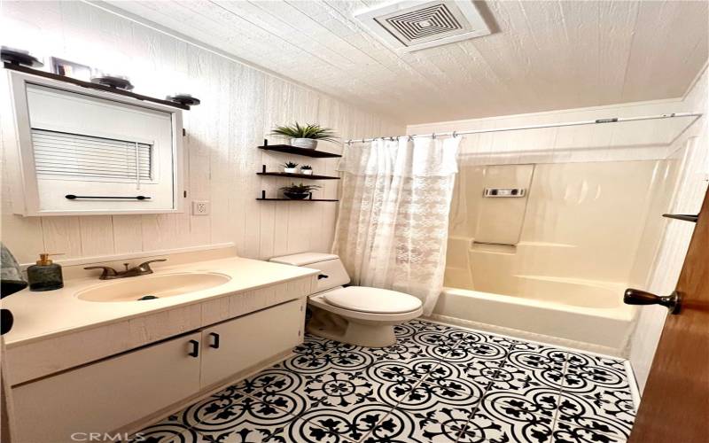 Tastefully decorated full bathroom with bathtub and shower, conveniently located by both bedrooms.