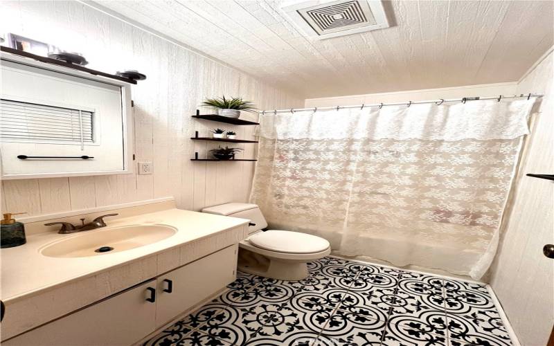 Tastefully decorated full bathroom with bathtub and shower, conveniently located by both bedrooms.