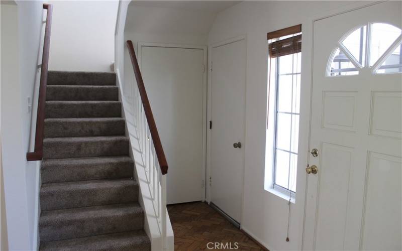 Staircase. To right (door handle out of view) is coat closet with under stairway storage. To right of that with handle is door to laundry area and garage.