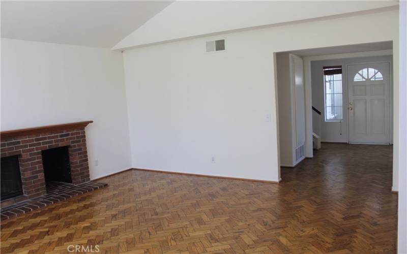 Family room with wood and gas burning fireplace. View is to front door.