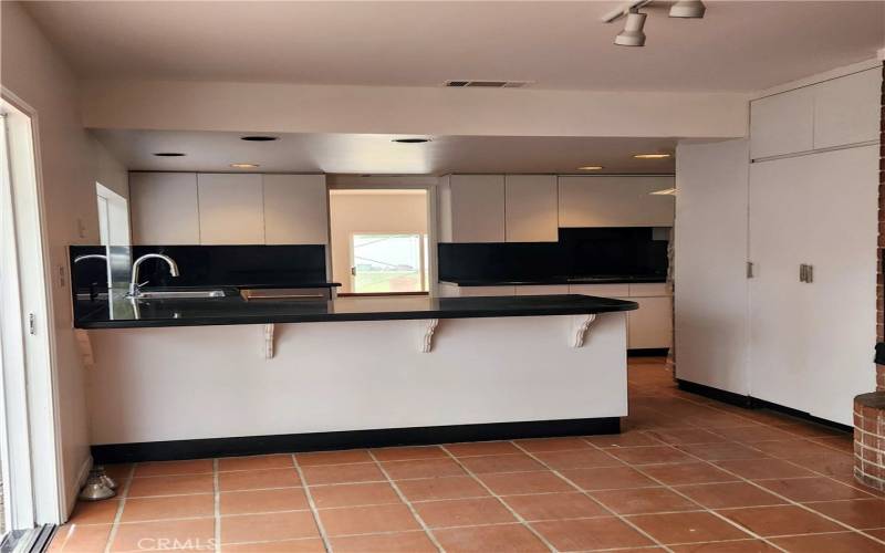 View from breakfast area to kitchen with large pantry, breakfast bar and black granite counters.