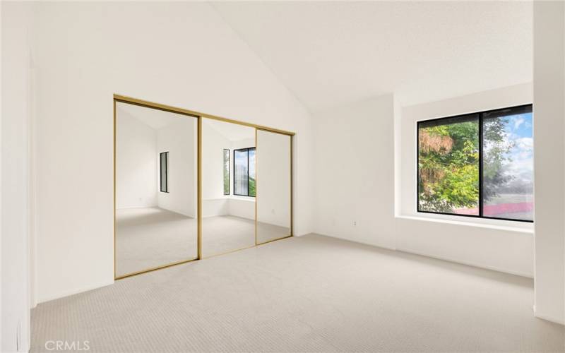 Large primary closet with mirrored doors.