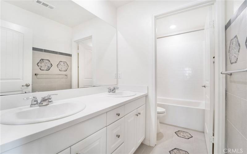 Upstairs bathroom features dual sinks, and custom designer tile work.