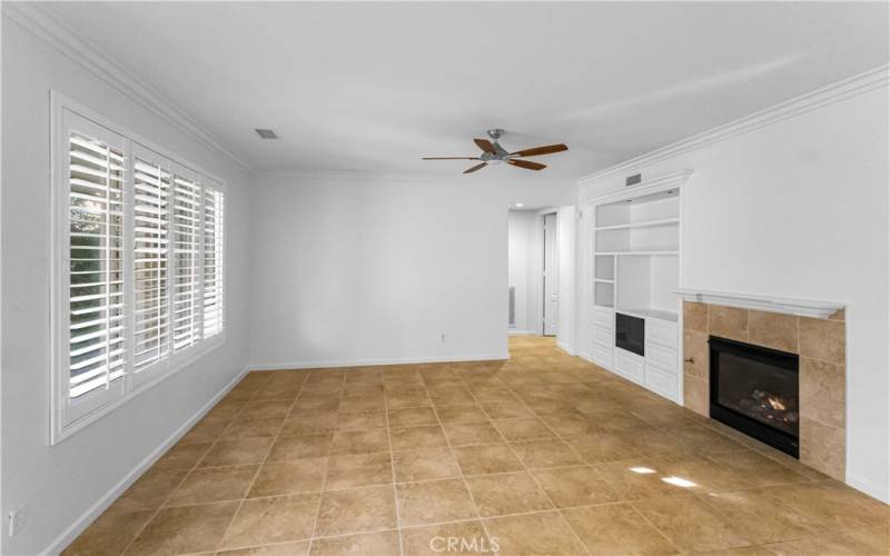 Family room has fireplace with mantle, ceiling fan, shutters and crown molding