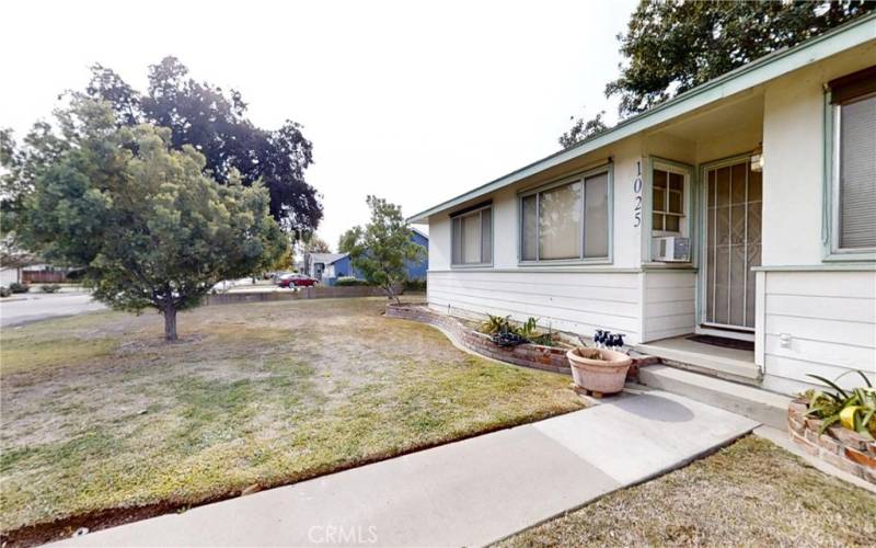 Large front yard with brick planters and trees.