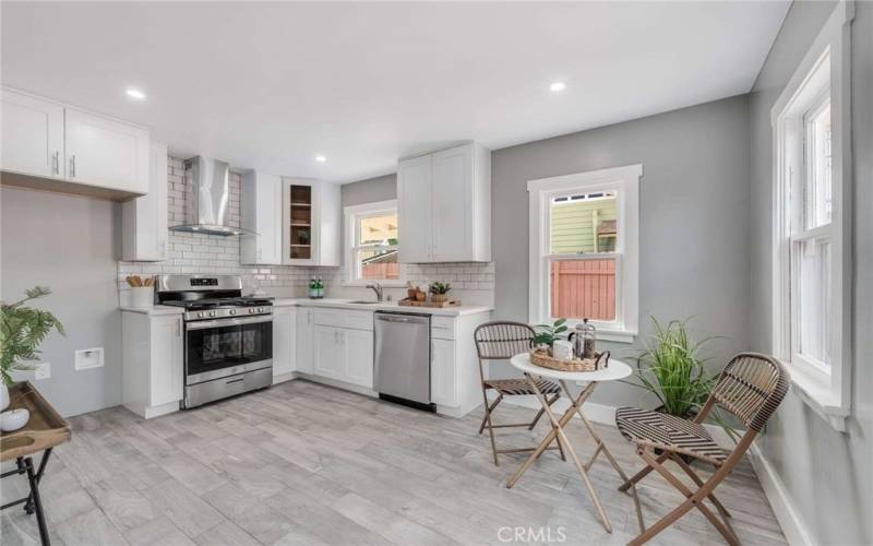 Darling kitchen with stainless steel appliances, quartz countertops, beautiful cabinetry, and cozy dining area