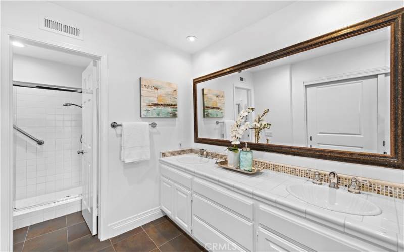 Primary bathroom with 2 sinks and a walk-in shower in the next room.