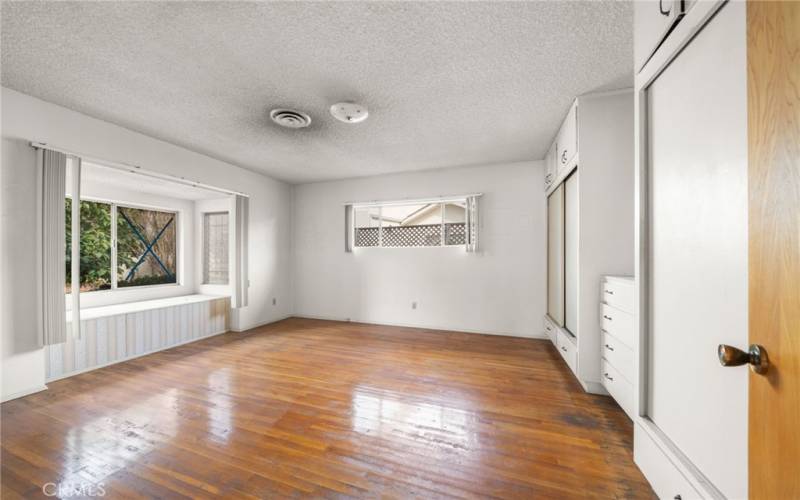 Primary bedroom with hardwood floors and a window seat