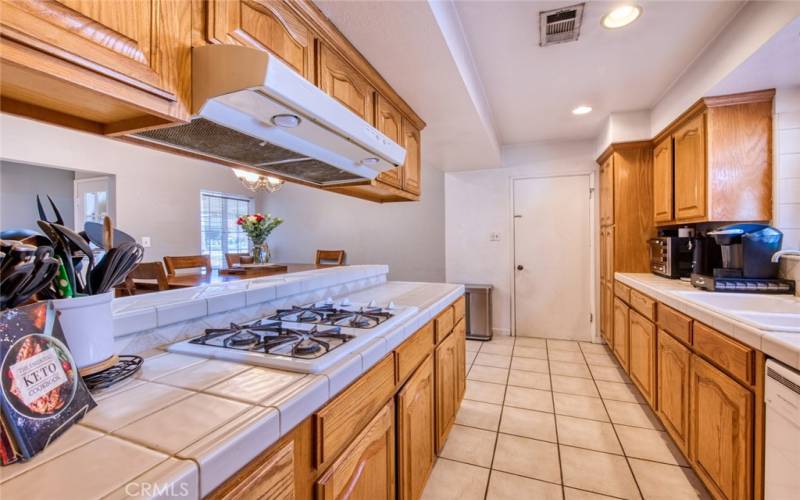 Kitchen boasts custom oak cabinetry, with tile countertops and gas cooktop.