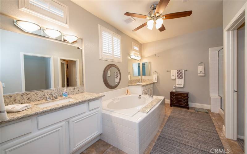 Fabulous remodeled master bathroom with separate granite vanities, tub, shower, ceiling fan, walk-in closet with mirrored door and privacy commode.