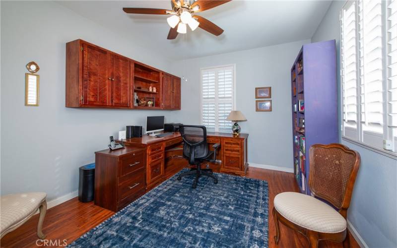 The front guest bedroom has wood type laminate floors, a ceiling fan and built-in cabinets.