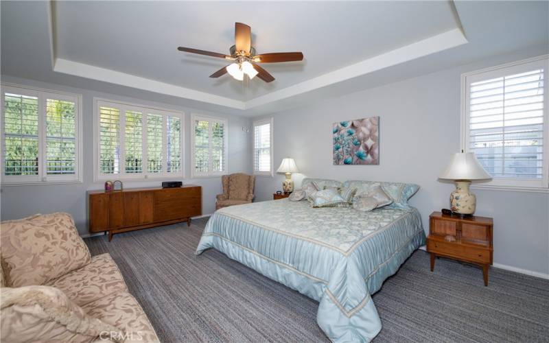 Elegant master bedroom with greenbelt views, coffered ceiling and ceiling fan.