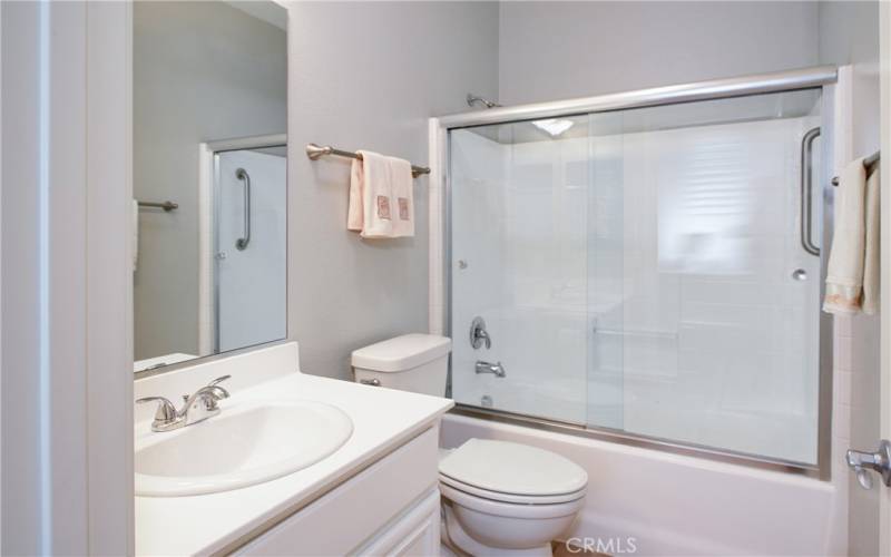 The guest/hall bath has tile floors, solar tube light and vanity with pull-out shelve.