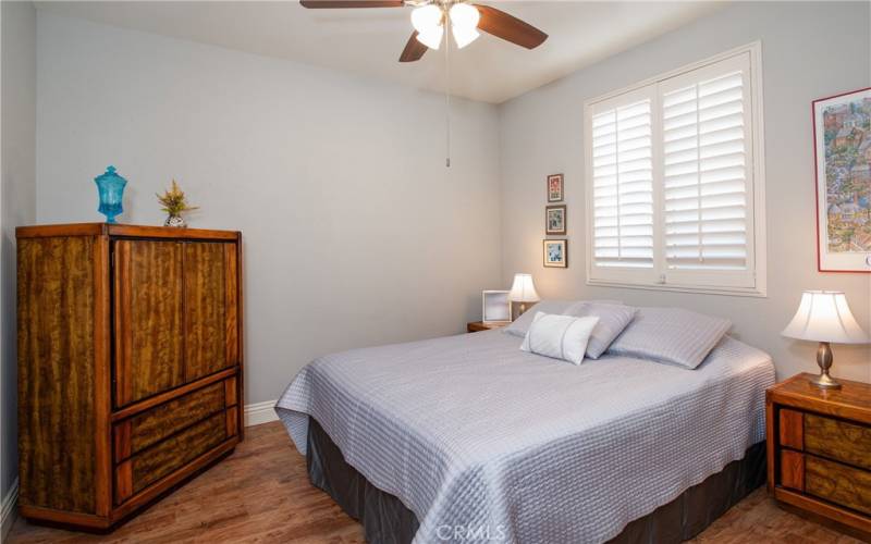 Generous sized guest bedroom with wood type laminate floors and ceiling fan.