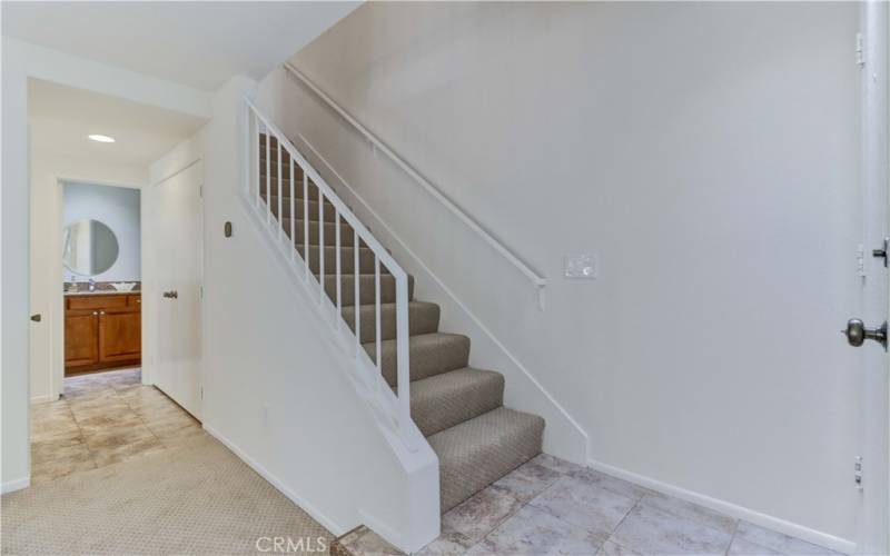 Laundry to right of half bath and kitchen.  Entry way to home at stairs.