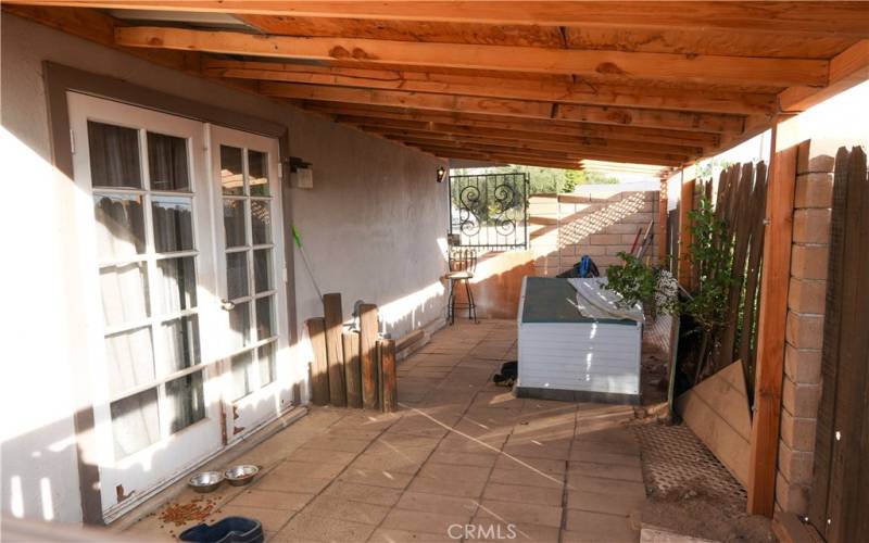 Side patio with french doors and rod iron gate for private entrance/used as dog area.