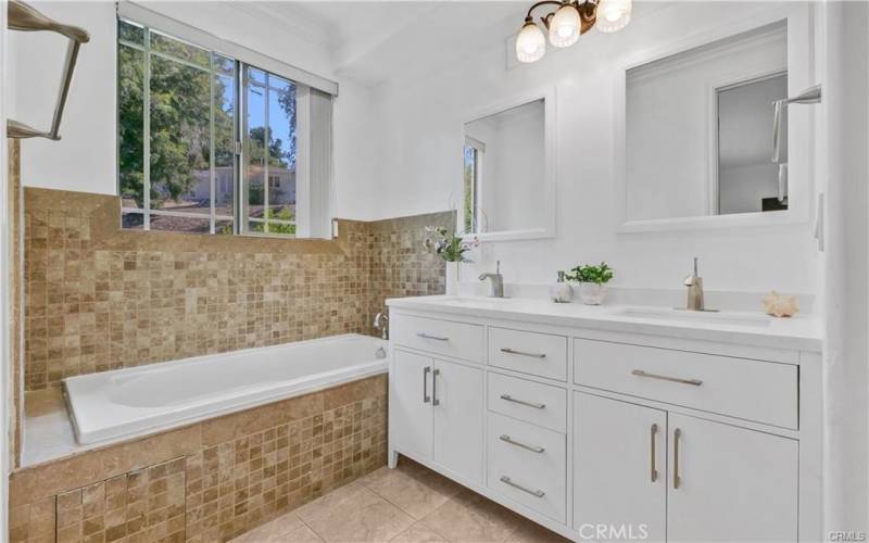 Primary bathroom w/ new double sink vanity, Quartz counters, Spa tub, shower & view of trees