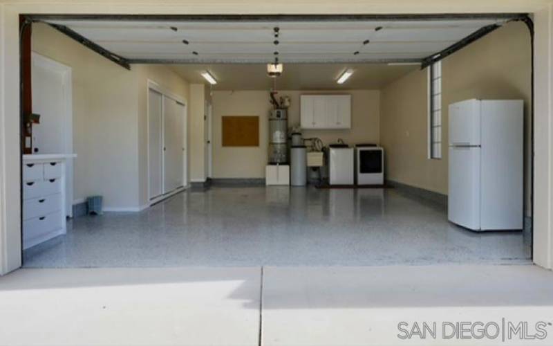 Two car attached garage with ample storage, second refrigerator, and washer and dryer