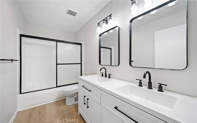 There is a remodeled full hallway bathroom with a shower/tub, dual vanity sinks, matte black finishes, light fixtures and laminate floors!
