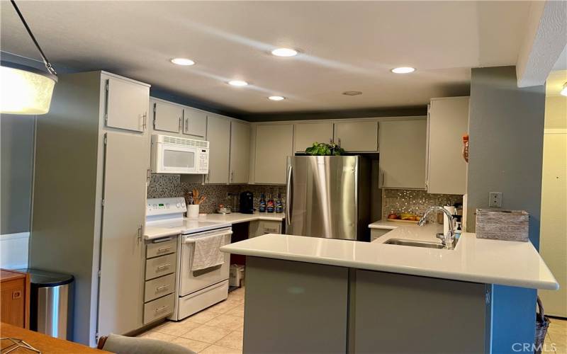 Remodeled kitchen with Quartz counters and new door hardware opens to dining and living room