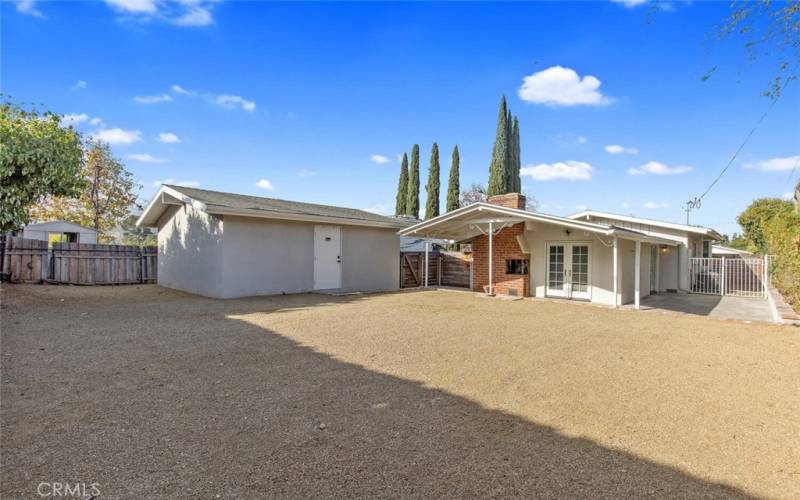 Large Back Yard with DG area. Visible are the detached Garage, house, and gated side yard with raised planter area.