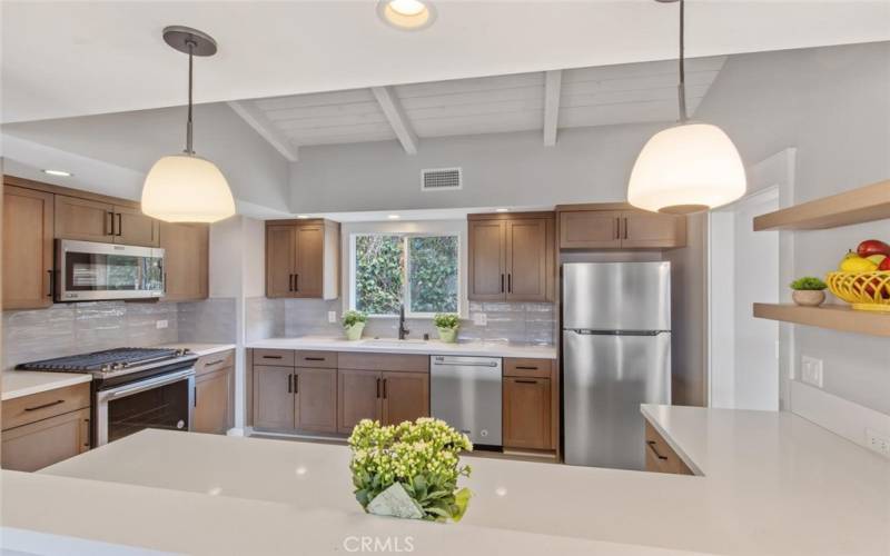 Stylishly Updated Kitchen with white quartz counter, subway tile back splash, Stainless appliances, and recessed overhead lighting.