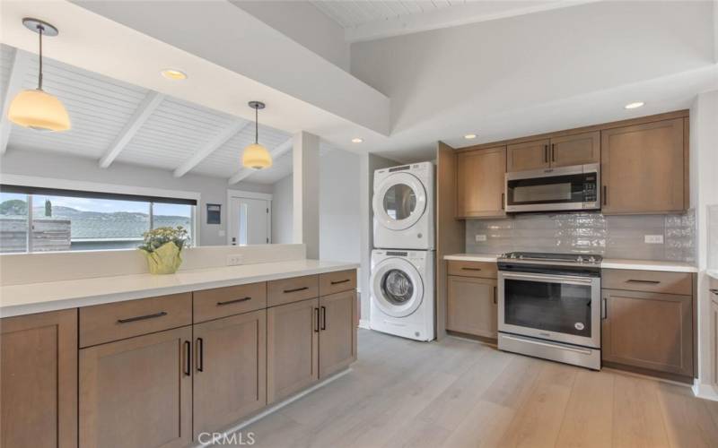 The Kitchen overlooks the Front Room and entrance. Featured are stackable Washer and Dryer, stainless convection range, microwave, and updated soft-close cabinets and drawers.