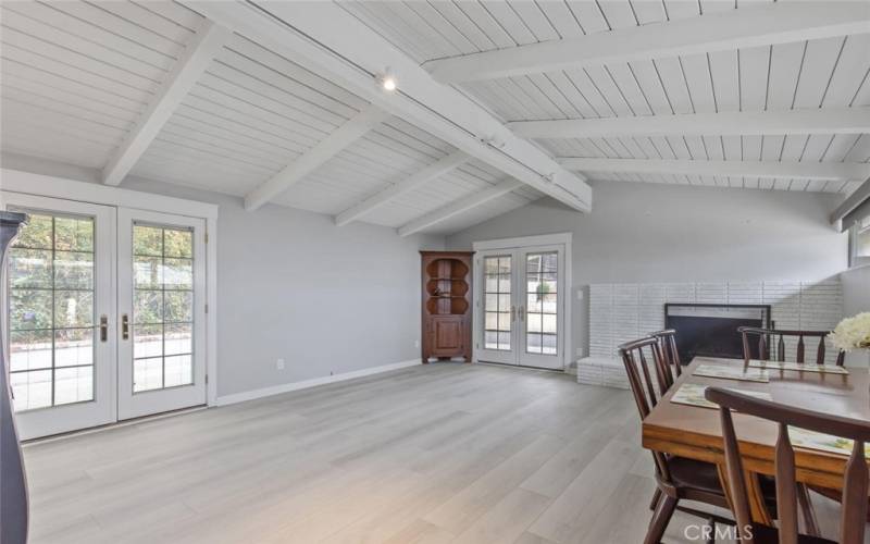 Family Room features a painted brick fireplace, French Doors (Pella) with internal mini-blinds, and NEW Vinyl Plank flooring (in Amarillo Pearl by Republic).