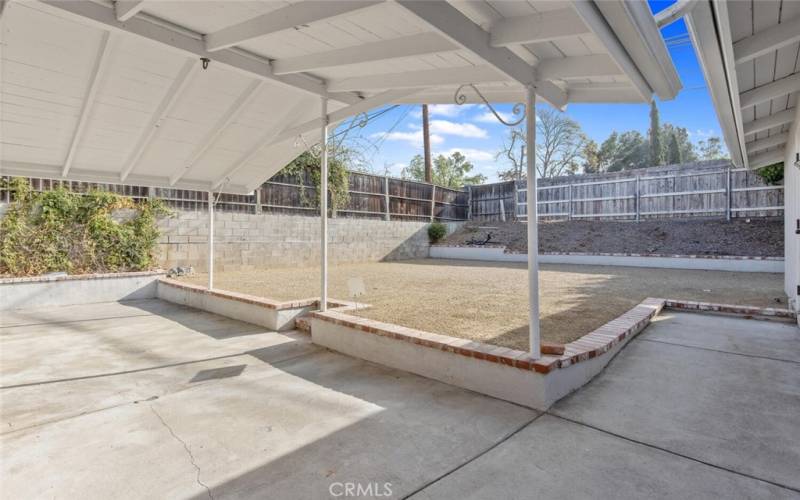 Going out the French doors, the Back yard is fenced, with a covered concrete patio, decomposed granite area, and planter areas.