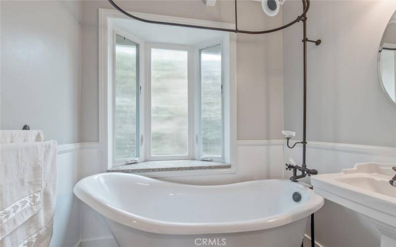 The deep bathtub with shower overhead is perfect for bubble baths and a long soak. The window overlooks the side yard, and is obscured for privacy.