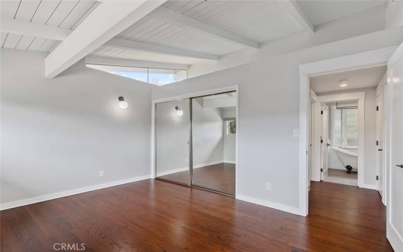 Bedroom #1 Primary with mirrored closets doors, wood floor.