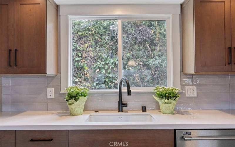 Kitchen sink window overlooks the fenced side yard and planter.