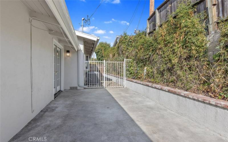 The Side Yard with Brick-trimmed raised planter and white wrought iron gate.