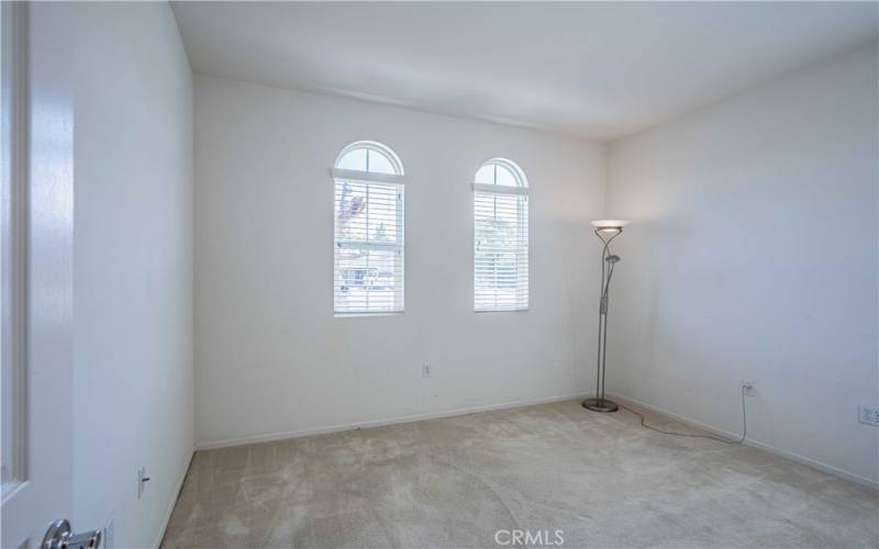 Secondary bedroom down the hallway is carpeted with windows.