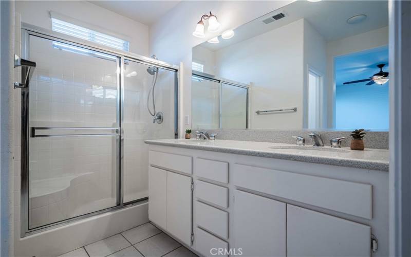 Primary bedroom has 2 sinks with quartz contertops, and stainless steel faucets, mirror and lights above. . Walk-in shower with window above.