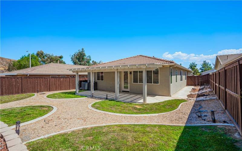 Back yard is darling with an alumawood patio that has concrete underneath, and pull down shades for privacy. 5 distinct grass areas trimmed in a rock path. Wood fence surrounds you.Concrete path  also on the side of the home.